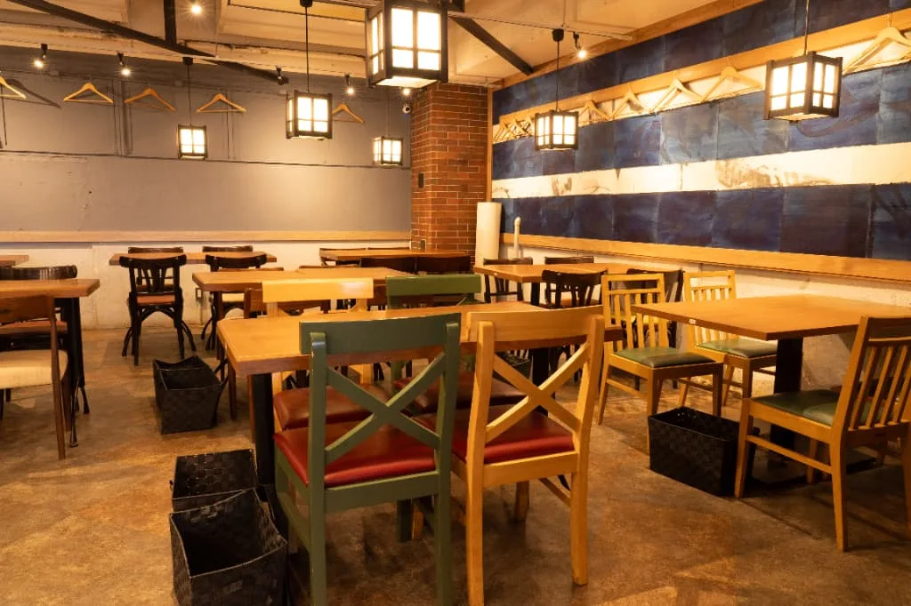 ちゅるりの店内。藍色の壁と行灯風の照明、木のテーブル席が並ぶ宴会フロア